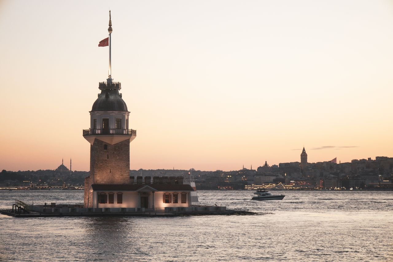 The scenic view of Maiden's Tower during sunset in Istanbul, Türkiye, with cityscape and boat.