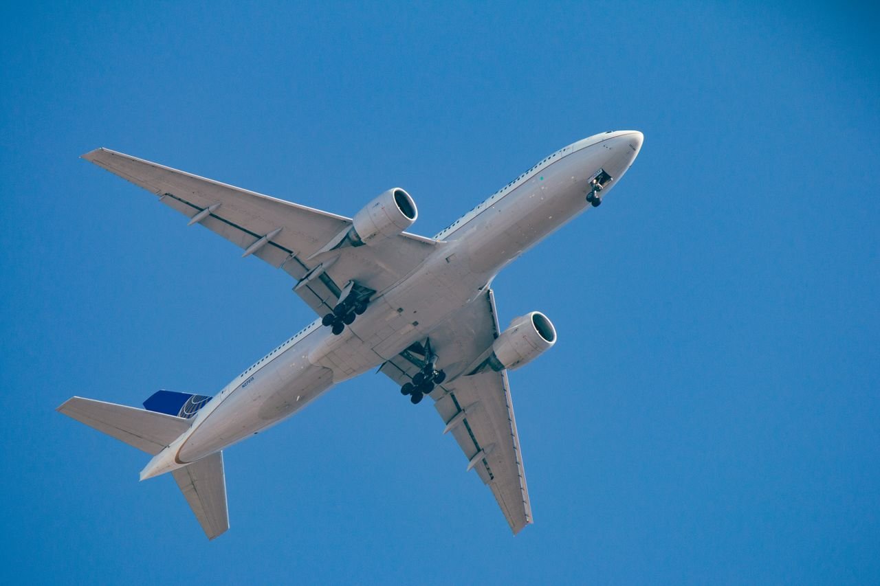 A commercial airplane captured midair against a clear blue sky, showcasing its design and power.